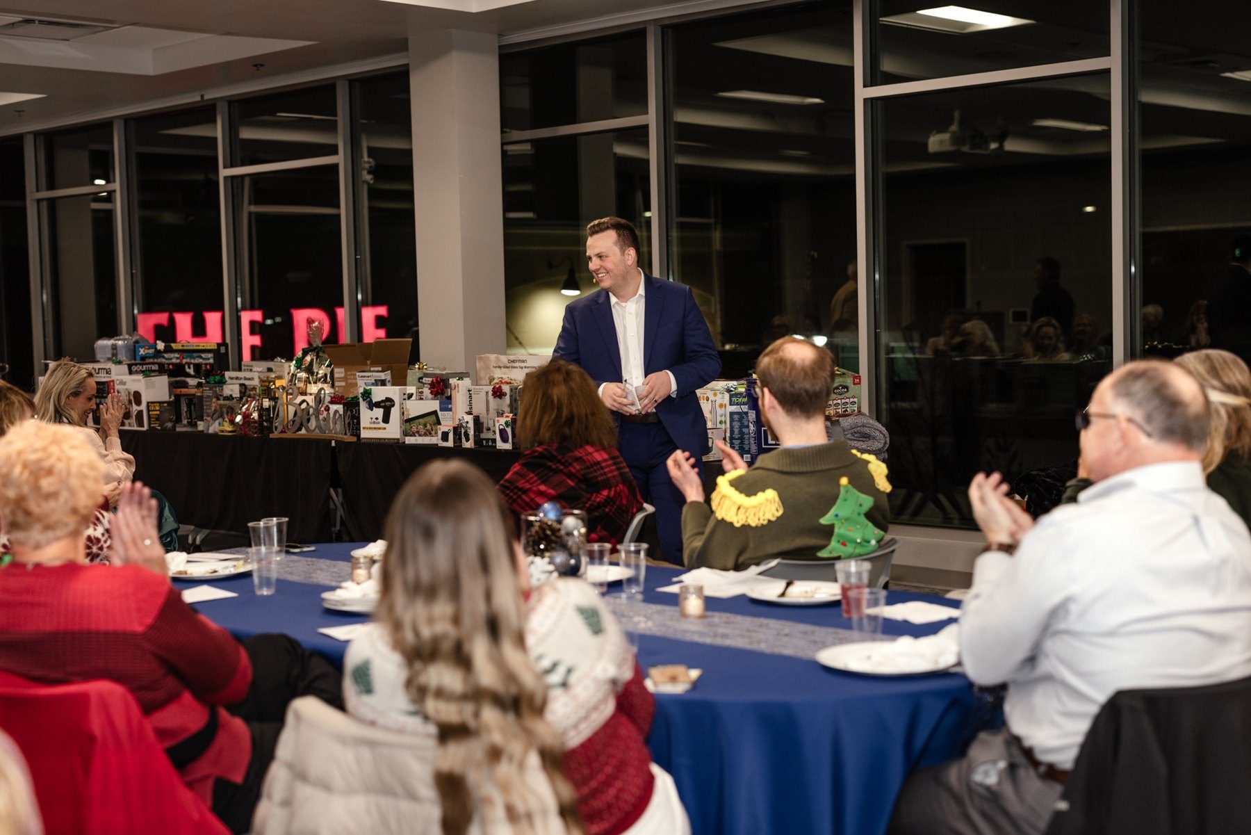 A full company holiday party room during Tyler August's performance
