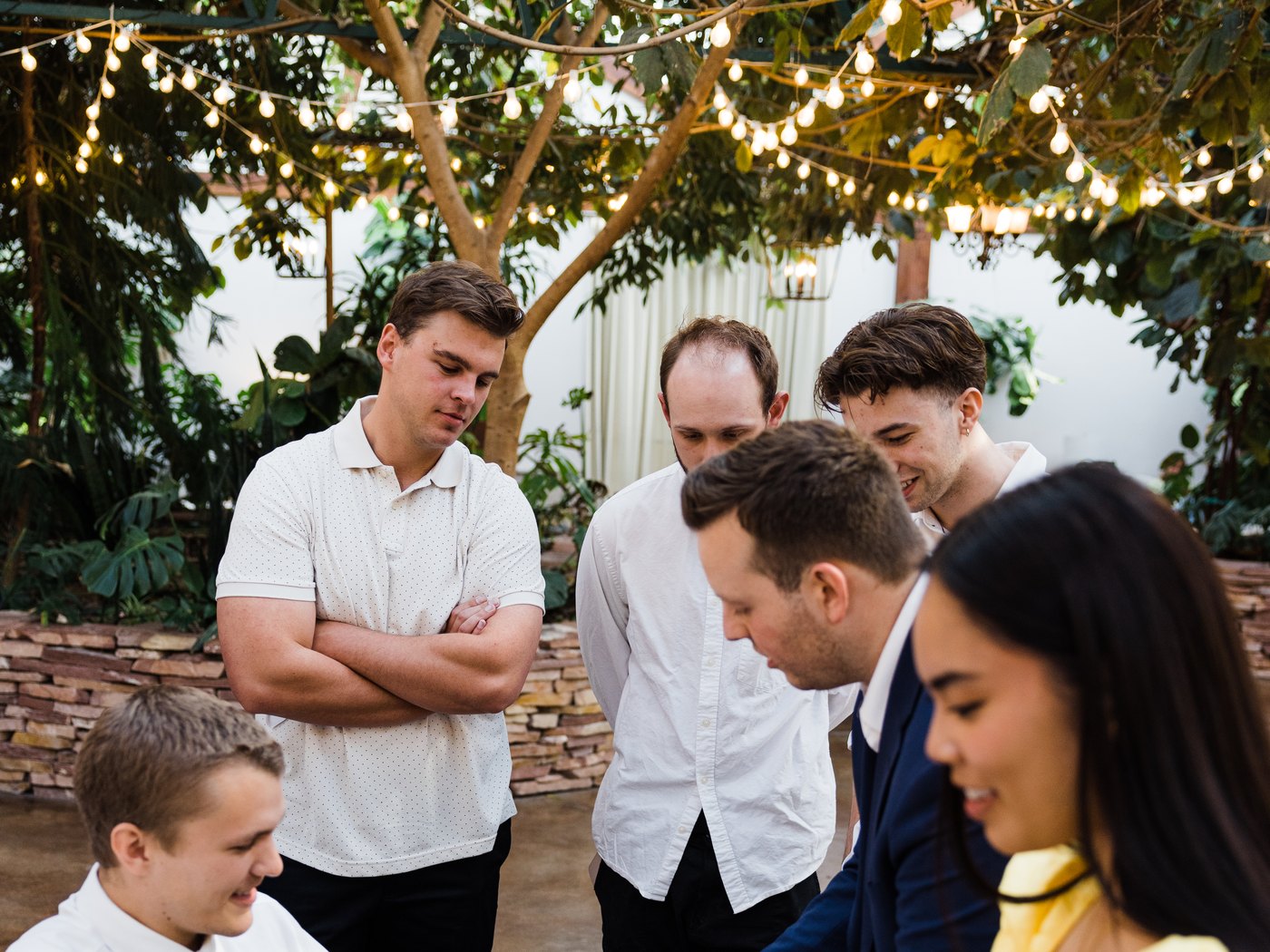 A group of wedding guests gathered around Tyler August during cocktail hour